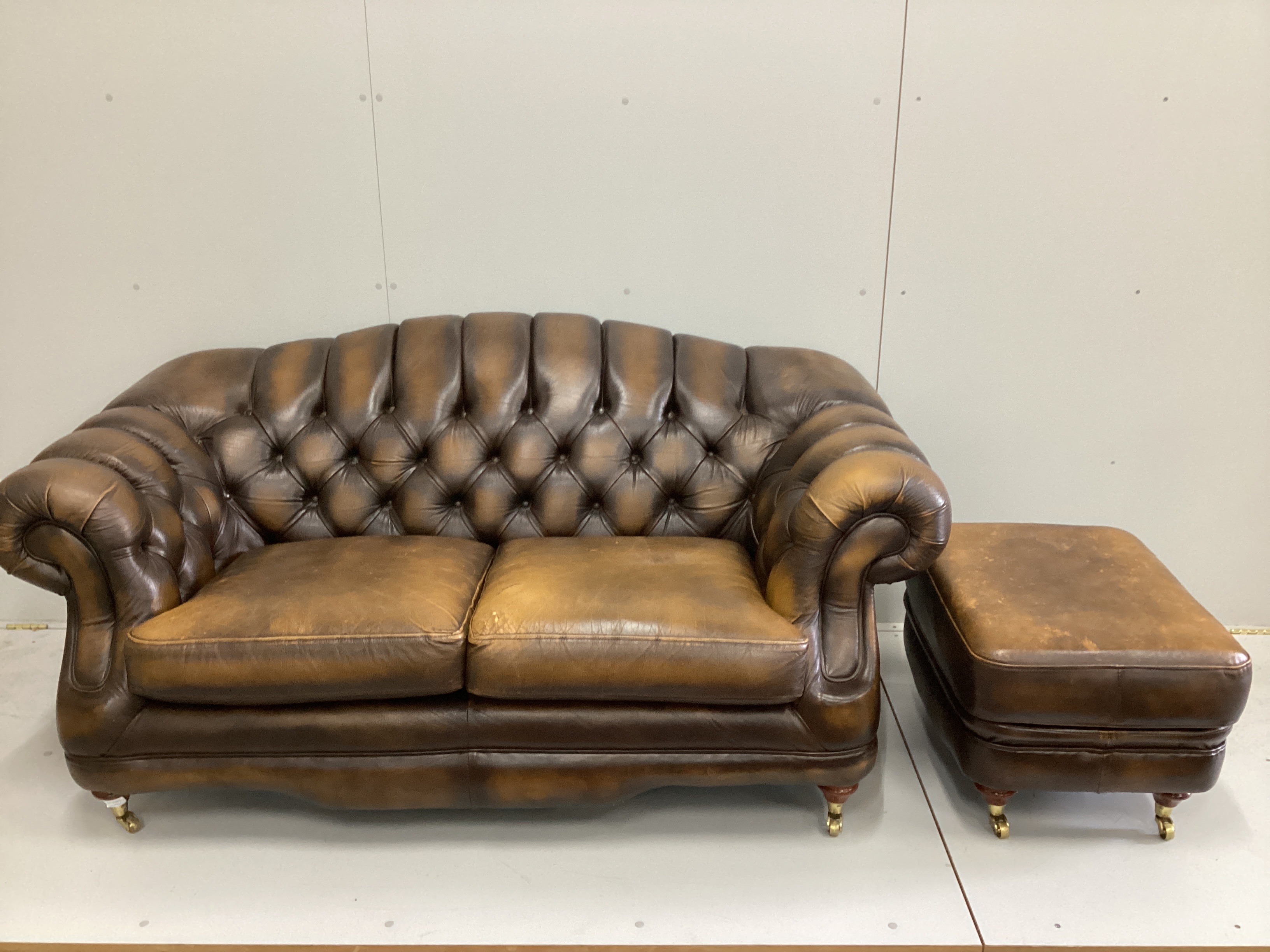 A Thomas Lloyd buttoned brown leather three seater settee, a two seater settee and a footstool, largest length 216cm, depth 90cm, height 85cm